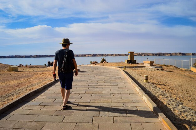 Closeup shot of a male walking on a road near the sea on a sunny day