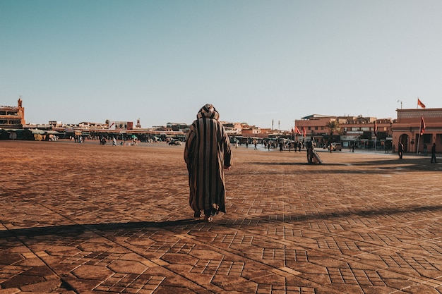 Closeup shot of a male walking in the town under a blue sky