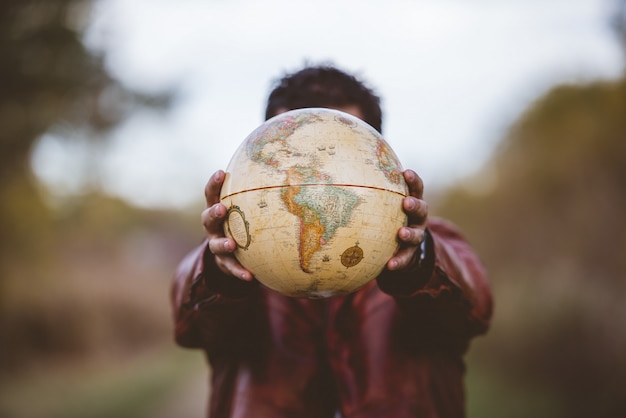 Closeup shot of a male wearing a leather jacket holding a globe in front of him