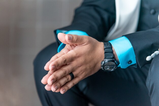 Closeup shot of a man in a suit holding his hands together while waiting