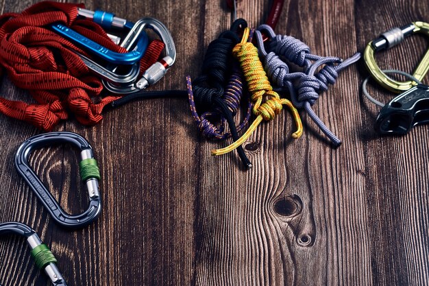 Closeup shot of many colorful climbing carabiners and knots on a wooden surface