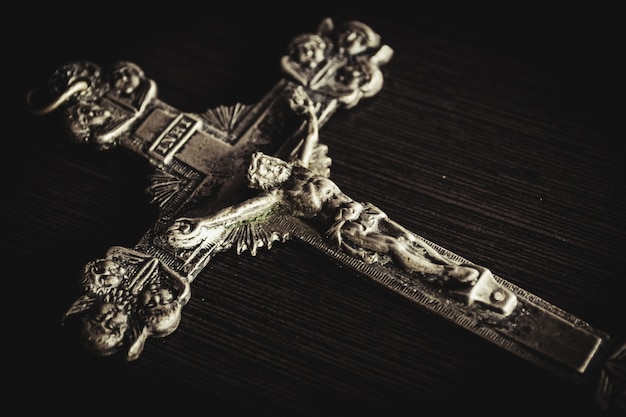 Closeup shot of a metal cross on a wooden black table