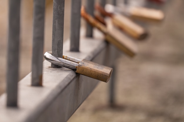 Closeup shot of metal padlocks with a heart hanging on a fence