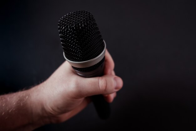 Closeup shot of a microphone in the hand of a person on black