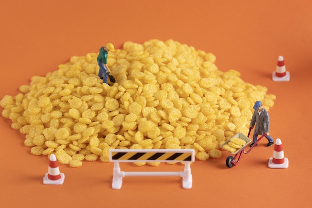 Free photo closeup shot of miniature labor figures on a pile of corn on orange surface