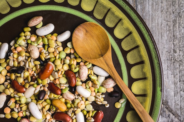 Free photo closeup shot of mixed beans in a plate with a wooden spoon