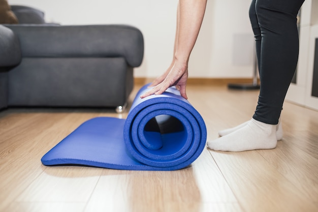 Бесплатное фото Снимок крупным планом женщины, складывающей синий коврик для йоги после тренировки дома