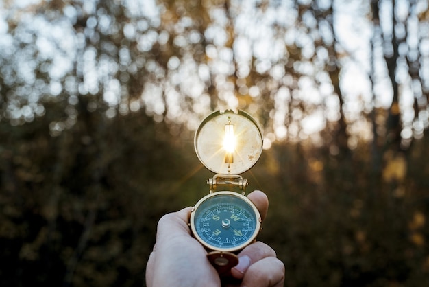 Бесплатное фото Снимок крупным планом человека, держащего компас с солнцем, сияющим через отверстие