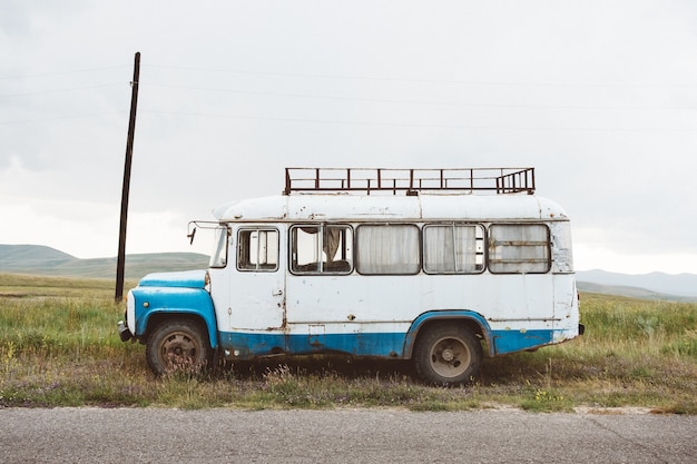 Closeup shot of an old minibus on a green landscape under a cloudy sky