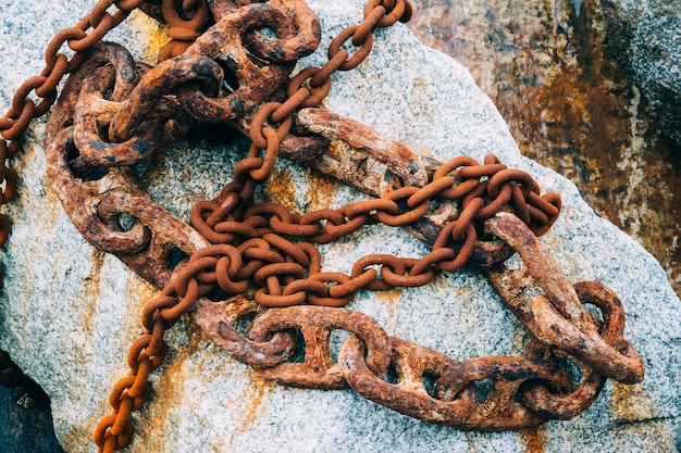 Closeup shot of an old rusty chains placed on the rock