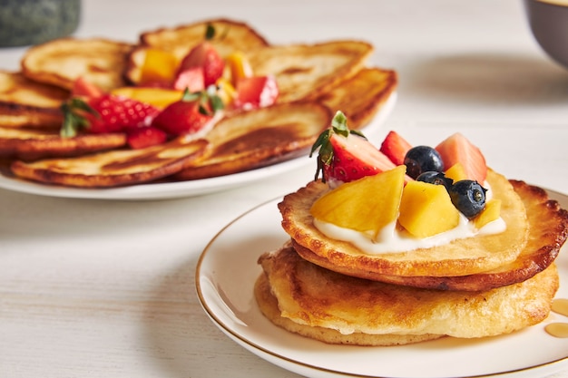 Closeup shot of pancakes with fruits on the top at breakfast