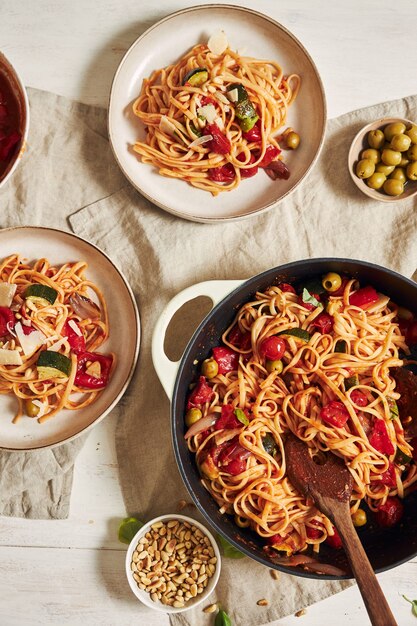 Closeup shot of pasta with vegetables and ingredients on a white table