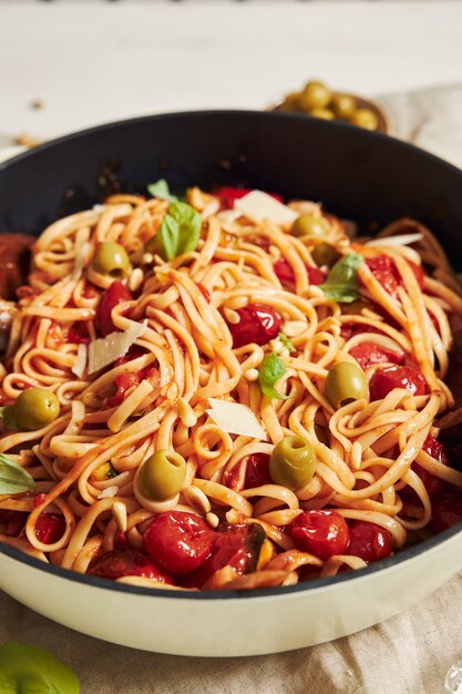 Closeup shot of pasta with vegetables and ingredients on a white table