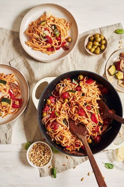 Closeup shot of pasta with vegetables and ingredients on a white table