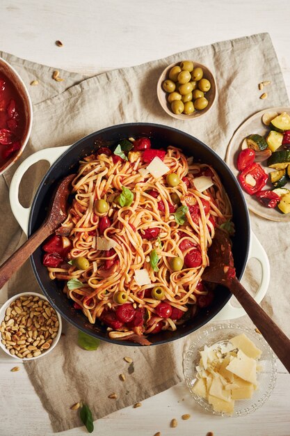 Closeup shot of pasta with vegetables and ingredients on a white table