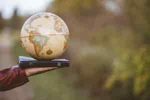 Free photo closeup shot of a person holding bible with desk globe on top