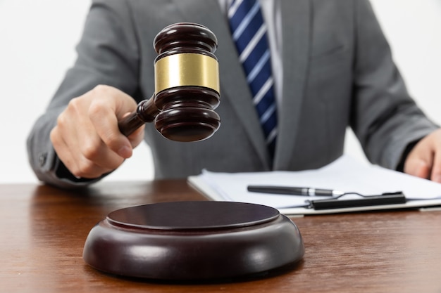 Closeup shot of a person holding a gavel on the tabl