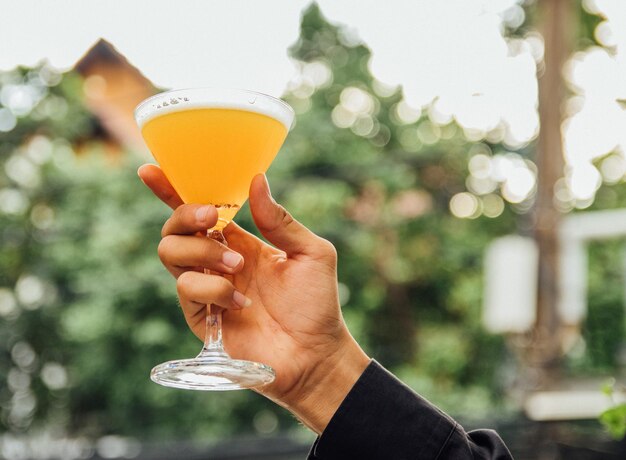 Closeup shot of a person holding a glass of beer on a blurred background