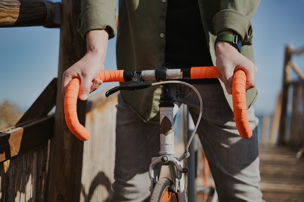 Closeup shot of a person holding an orange bike handlebar