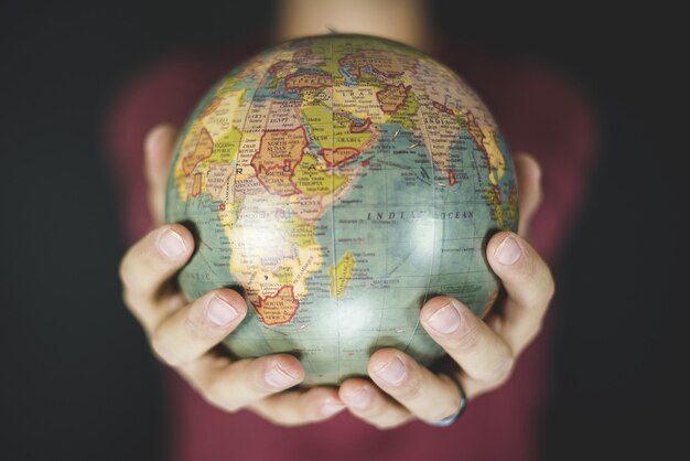 Closeup shot of a person holding a small globe with two hands