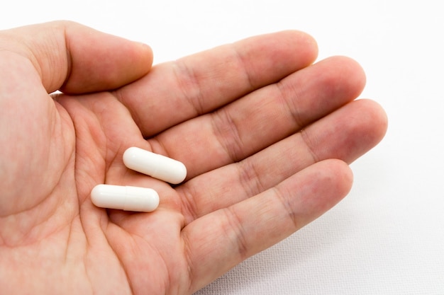 Closeup shot of a person holding two white capsules