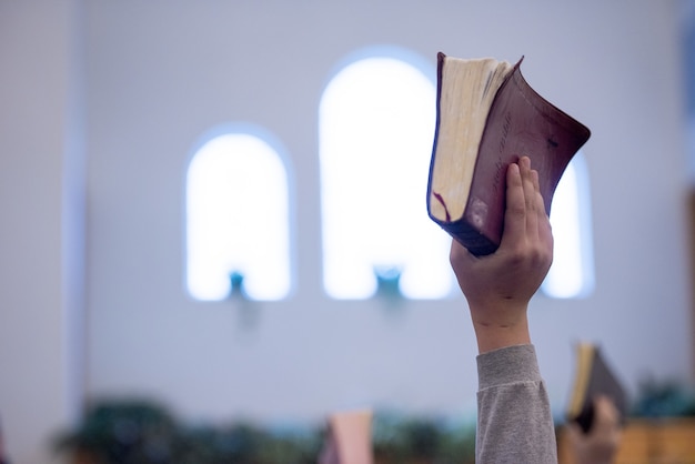 Снимок крупным планом человека, держащего библию на размытом фоне