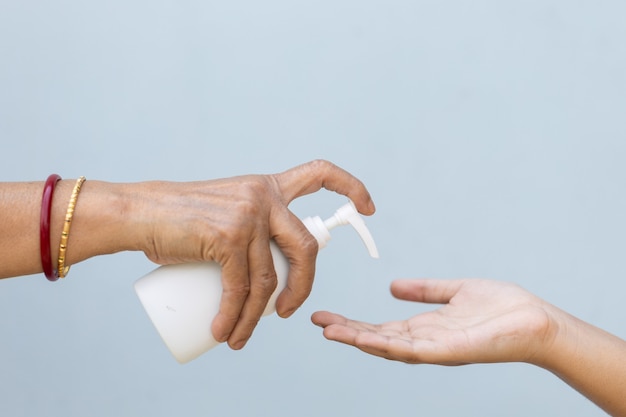 Снимок крупным планом человека, наливающего жидкое мыло в руку другому человеку