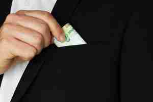 Free photo closeup shot of a person putting some cash in the pocket of his coat