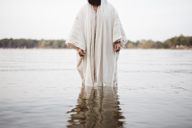 水に立っている聖書のローブを着ている人のクローズアップショット