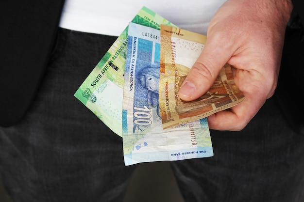 Снимок крупным планом человека в костюме, держащего деньги в руке
