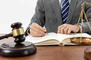 Free photo closeup shot of a person writing in a book with a gavel on the table