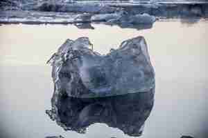 Foto gratuita colpo del primo piano di un pezzo di ghiaccio che galleggia nell'oceano e riflesso in esso a jokulsarlon, islanda