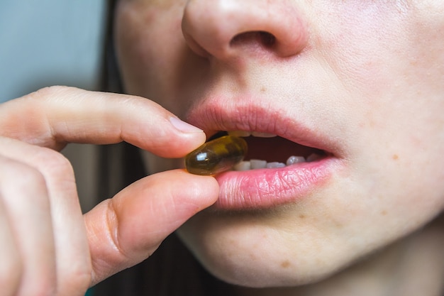 Foto gratuita colpo del primo piano di una pillola tra i denti di una donna