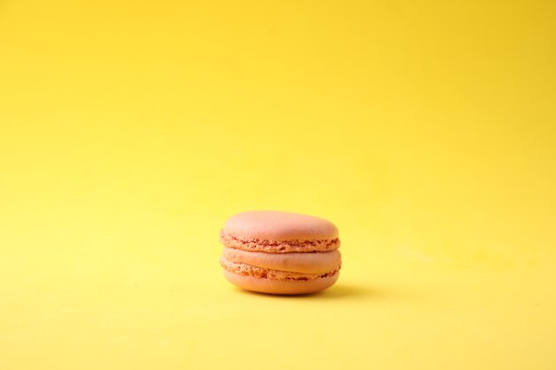Closeup shot of a pink macaroon on a yellow background
