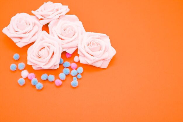 Closeup shot of pink roses and colorful pompons isolated on orange background