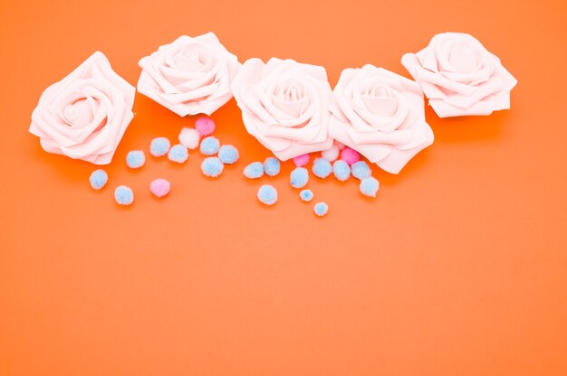 ピンクのバラとオレンジ色の背景に分離されたカラフルなポンポンのクローズアップショット