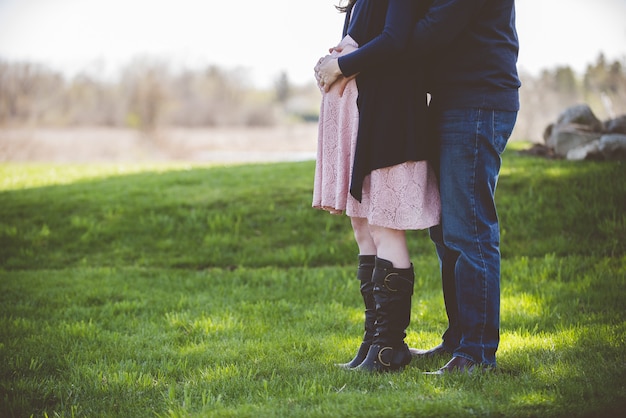 Closeup shot of a pregnant couple standing on a grassy field