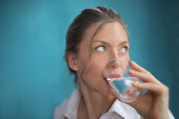 Closeup shot of pretty female drinking water on blue