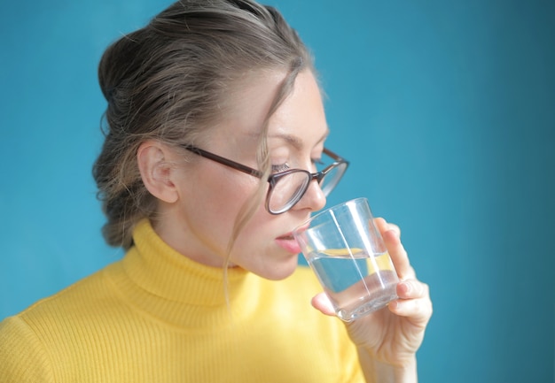 Closeup shot of pretty female with yellow top drinking water