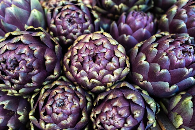 Closeup shot of purple artichokes neatly stacked in a market
