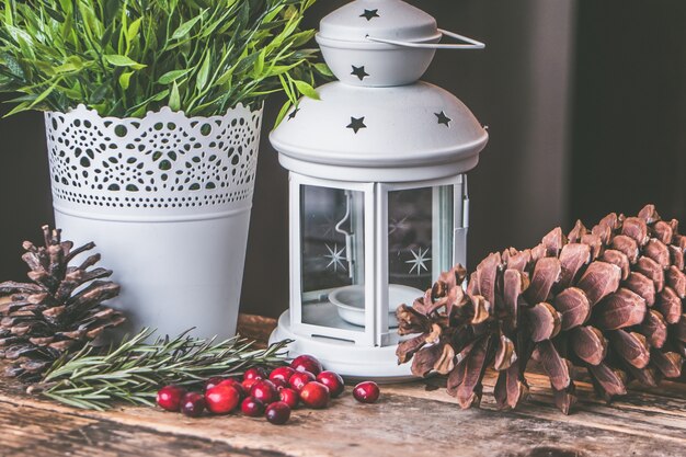 Closeup shot of red coffee beans and a pinecone with a candle lantern on a wooden surface