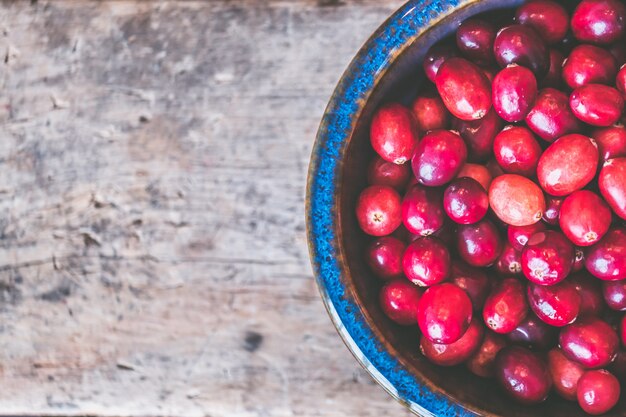 Closeup shot of red coffee beans on a wooden gray surface