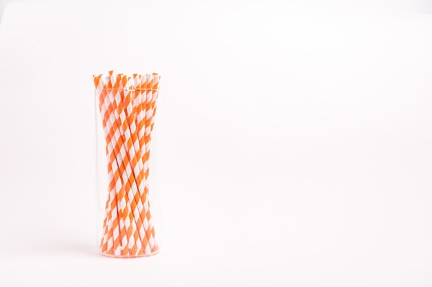 Closeup shot of red and white striped drinking tubes in a glass isolated on a white surface