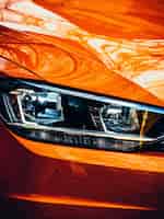 Foto gratuita colpo del primo piano del faro destro di un'auto moderna arancione