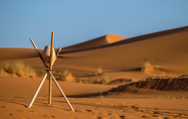 Closeup shot of a rock on a stick tripod with blurred sand dunes