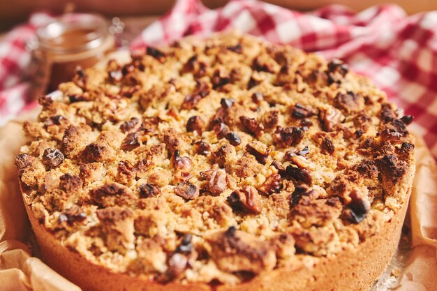 Closeup shot of a round apple pie topped with crumble and roasted nuts, on a towel