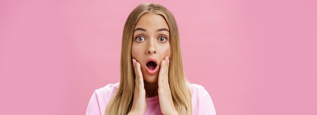 closeup shot of shocked young female student with tanned skin and fair hair dropping jaw gasping fro