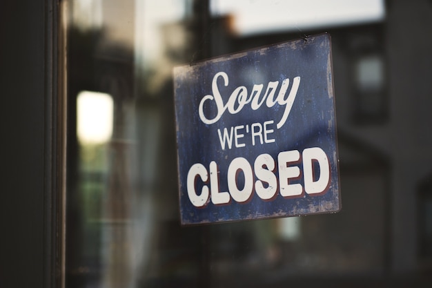 Closeup shot of a sign that says "Sorry We're Closed" hanging on a glass door