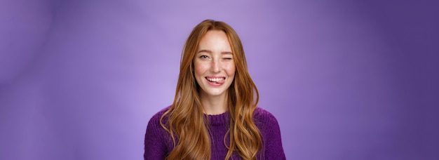 Closeup shot of sincere and happy funny cute redhead female with long ginger hair winking happily an