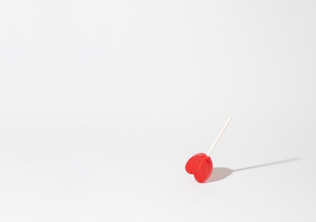 Closeup shot of a single heart-shaped lollipop on a white background